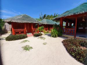 un complejo con un edificio con cabañas de paja en la playa en Pareja Tourist Inn, en Isla de Malapascua