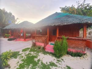 una casa con techo de paja en una playa en Pareja Tourist Inn, en Isla de Malapascua