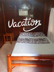 a bed with the word vacation written on the wall at Pareja Tourist Inn in Malapascua Island