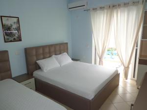 a bedroom with two beds and a large window at Olympian Rooms in Dhërmi