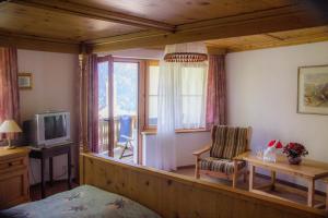 Cette chambre comprend un lit, une télévision et une chaise. dans l'établissement Hotel La Soglina, à Soglio