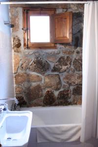 a bathroom with a tub and a window and a sink at La Quinta de los Enebrales in Hoyo de Pinares