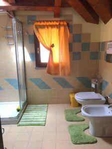 La salle de bains est pourvue de 2 toilettes et d'un rideau de douche orange. dans l'établissement B&B Fior di Loto, à Ceriale