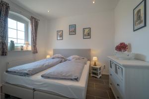 1 dormitorio con cama blanca y ventana en Ferienwohnung Hooge Hörn en Borkum