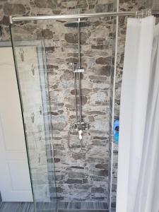 a shower with a glass door and a stone wall at Bestie House in Kotor