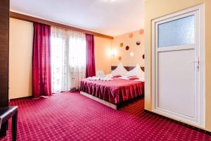 a hotel room with a bed and a sliding door at Pensiunea Dorali in Moieciu de Jos