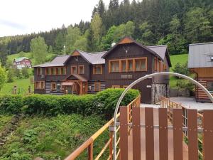 ein großes Holzhaus mit einem Zaun davor in der Unterkunft Pension Čertice in Pec pod Sněžkou