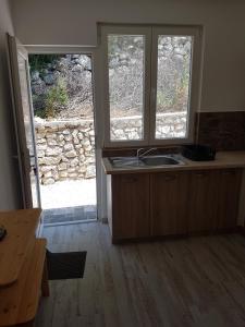 uma cozinha com um lavatório e duas janelas e um balcão em Bestie House em Kotor