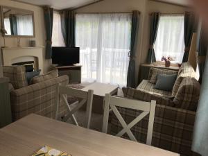 a living room with a couch and a table at Deluxe Riverside Static Caravan in Cheddar