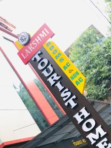 un panneau indiquant un hôtel situé sur le côté d'un bâtiment dans l'établissement LAKSHMI TOURIST HOME, à Guruvāyūr