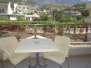 a white table and chairs on a balcony with a view at Olympian Rooms in Dhërmi