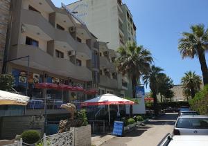 un edificio con una sombrilla y coches estacionados frente a él en Hotel Palma, en Durrës