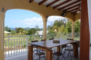 porche con mesa de madera y sillas en el balcón en villa stenella, en Bouillante