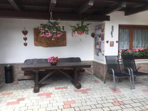 un tavolo in legno con sedie e fiori su un patio di Garni La Vara a Corvara in Badia