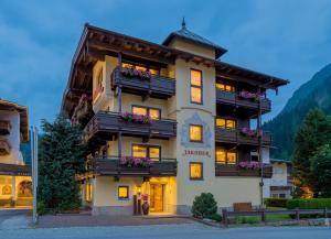 ein großes Gebäude mit Blumen auf den Balkonen in der Unterkunft Hotel-Garni Jakober in Tux