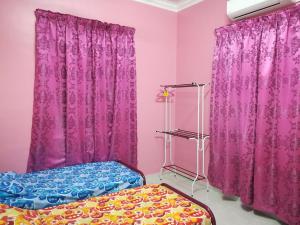 Habitación rosa con cama y cortinas moradas en HOMESTAY DAMAI YUSMILA en Kuala Terengganu