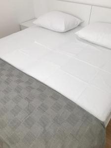 een bed met witte lakens en 2 kussens bij Sea View Apartments Zaboric in Zaboric