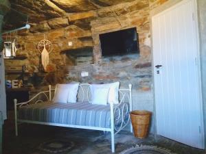 a bedroom with a bed with a tv on a stone wall at Gaia Vacation Home in Agia Mavra