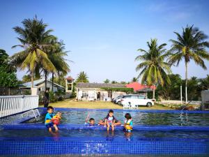 a group of children playing in a swimming pool at ALA Beach Lodge - Markisa Homestay in Bachok