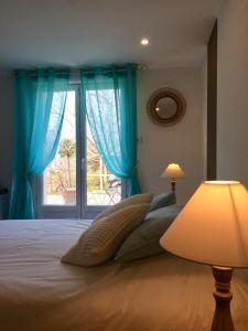 una camera da letto con un letto con tende blu e una finestra di Le Mapillon a Dieulefit