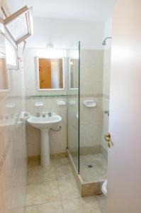 uma casa de banho branca com um lavatório e um chuveiro em Hotel Marydor em La Falda