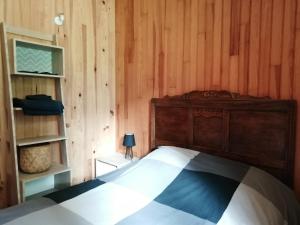 sypialnia z łóżkiem i drewnianą ścianą w obiekcie Le Grand Saule w Aston