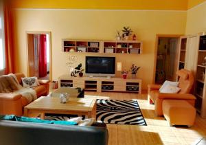 sala de estar con muebles de color naranja y TV de pantalla plana. en Apartment Villa Frank en Mariánské Lázně