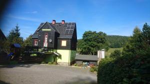 una casa verde y negra con paneles solares. en Gästehaus Meierbaude, en Kurort Altenberg