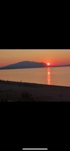 a sunset on the beach with the sun setting over the water at Villa Un bel posto Sea View in Nea Vrasna