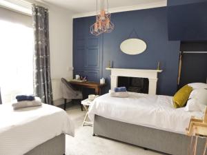 a blue bedroom with two beds and a desk at Rosalind House in Carlisle
