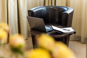 a laptop computer sitting on a table in a chair at City Avenue Hotel by HMG in Sofia
