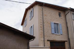 un bâtiment avec des fenêtres bleues sur son côté dans l'établissement Aux Portes du Beaujolais, à Belleville-sur-Saône