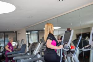 a woman riding on a treadmill in a gym at Links Country Park Hotel in Cromer +33 photos