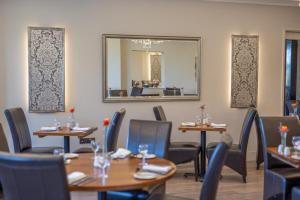 a dining room with tables and chairs and a mirror at Links Country Park Hotel in Cromer