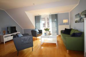 een woonkamer met een groene bank en stoelen bij Fewo Schildknecht in Bad Zwischenahn