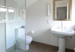 a white bathroom with a toilet and a sink at Victoria in Holkham