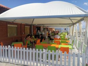 un padiglione bianco con tavoli e sedie colorati sulla spiaggia di B&B Crispino a Belvedere Marittimo