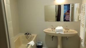a bathroom with a sink, mirror and bath tub at Hôtel Patton in Avranches