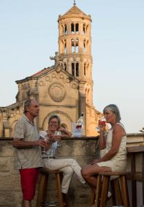 three people sitting on stools in front of a church at Boutique Hôtel Entraigues in Uzès