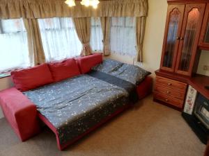 a bed in a room with a red couch and windows at Domki holenderskie na Mazurach in Dźwierzuty