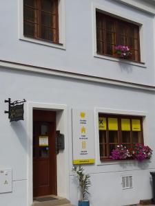 a white building with two windows with flowers on them at Penzion U Žabáka in Mikulov