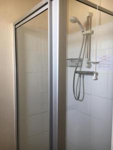 a shower with a glass door and a shower head at Chester Lodge in Sandown