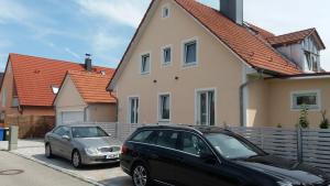 dos autos estacionados en un estacionamiento frente a una casa en Müller Residenz Zur S-Bahn Karlsfeld, en Karlsfeld