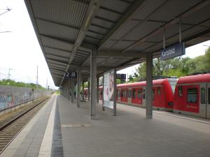 a train station with two red trains on the tracks at Müller Residenz Zur S-Bahn Karlsfeld in Karlsfeld