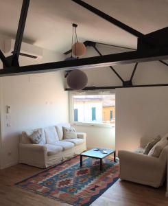 a living room with two white couches and a table at Cinema House Apartments in Orbetello