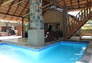 - une piscine dans une maison dotée d'un plafond en bois dans l'établissement Kruger River Holiday Home, à Marloth Park