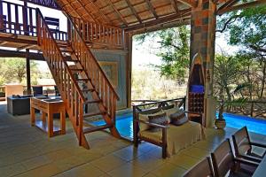 eine Terrasse mit einer Treppe, einem Tisch und Stühlen in der Unterkunft Kruger River Holiday Home in Marloth Park