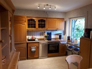 a kitchen with wooden cabinets and a sink at Ferienwohnung am Sorpesee in Allendorf