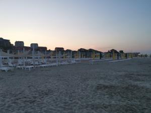 コンスタンツァにあるApartamente Sara 2013の夕日の白い椅子とパラソル付きのビーチ