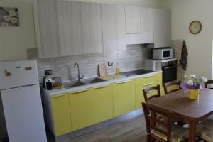 a kitchen with yellow cabinets and a table and a white refrigerator at Daniele Guest Apartment in Pistoia